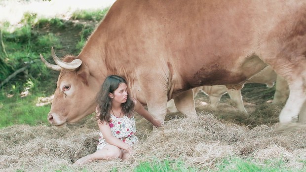Mädchen bei einer braunen Kuh sitzend
